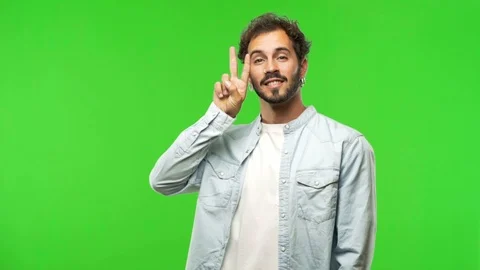 Young man on chroma green screen fun and happy doing a gesture of victory Stock Footage 97707402