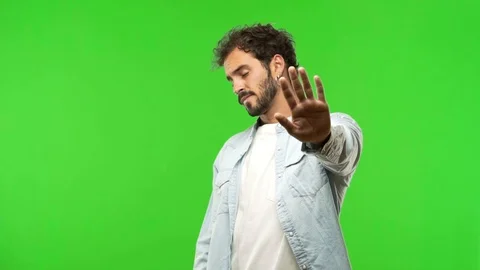Young man on chroma green screen putting hand in front Stock Footage 97707441