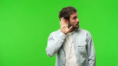 Young man on chroma green screen try to listening a gossip Stock Footage 97707476
