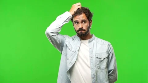 Young man on chroma green screen worried and overwhelmed 動画素材 97707667