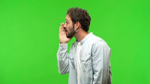 Young man on chroma green screen whispering gossip undertone Stock Footage 97707770
