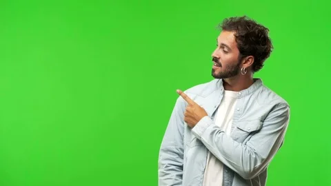 Young man on chroma green screen pointing to the side Stock Footage 97708104