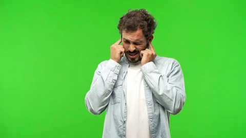 Young man on chroma green screen covering ears with hands Stock Footage 97708323
