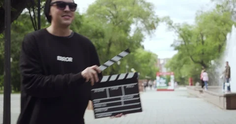 Young man with clapperboard appears and leaves the frame. Stock Footage 119997052