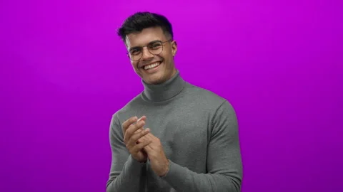 Young man clapping happily in glasses and sweater against vibrant pink back.. Stock Footage 315512827