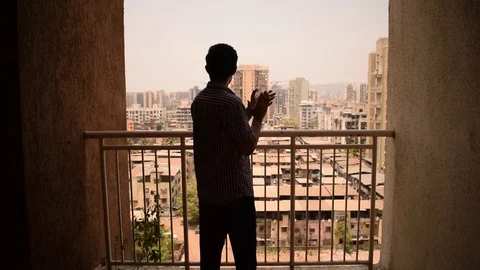 Young man claps hands in balcony to applaud health workers during coronavirus Stock Footage 128601790
