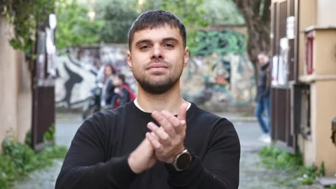 Young man claps hands with a soft, satisfied smile Stock Footage 306674548