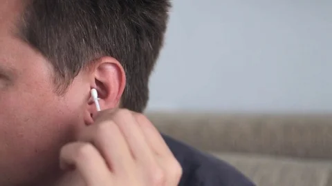Young man cleaning his ear with a cotton swab Stock Footage 79588945