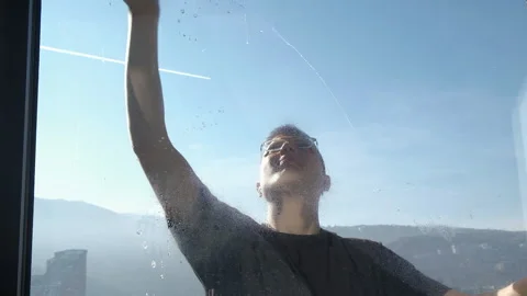 Young man cleaning the wide window glass with magnetic brush in slow motion Video stock 229892944