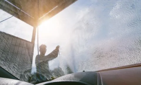 Young man cleaning windshield. Stock Photos