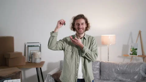Young man client bought new house, happy owner shaking a key in the air in his Stock Footage 171112527