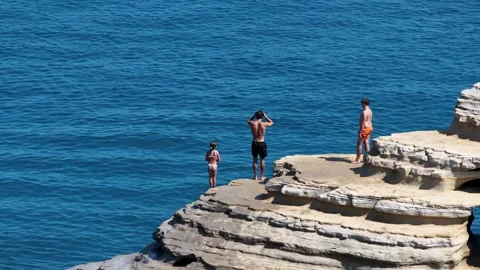Young Man Cliff Diving into the Turquoise Ionian Sea from Sandstone Rocks at Stock Footage 345388093