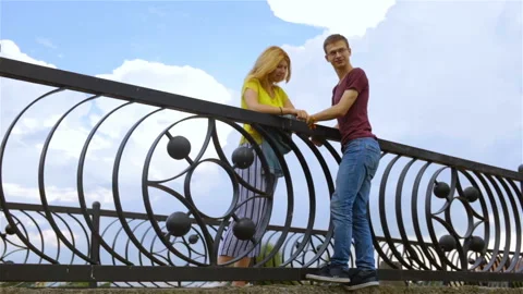 The young man climbed to the girl on the railing of the bridge. A man tries to i Stock Footage 101487598