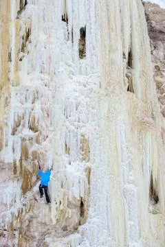 Young man climbing the ice using ice axe Stock Photos