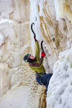 Young man climbing the ice using ice axe Foto stock