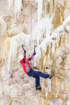 Young man climbing the ice using ice axe Stock Photos