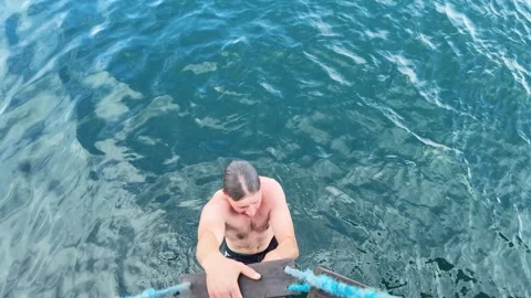 Young man climbing rope ladder onto boat Stock Footage 345617353