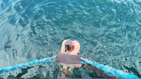 Young man climbing rope ladder onto boat slow motion Stock Footage 345617375