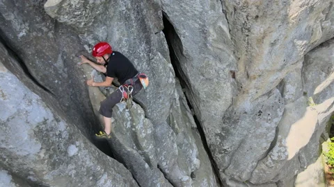 Young man climbing steep wall of rocky mountain. Male climber overcomes Stock Footage 167565605