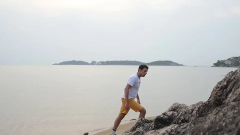 A young man climbs up the rocks without insurance, on the beach. slow motion Stock Footage 90608803