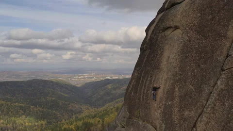 A young man climbs to the top of a mountain on a vertical wall with a great view Stock Footage 121914529
