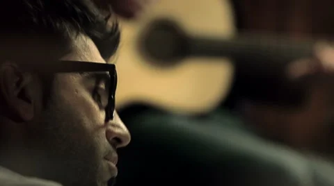 Young man close up is singing while is playing a guitar 動画素材 64513157