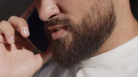 Young man close up talking with a friend on a smartphone and smiling contentedly Stock Footage 250625936