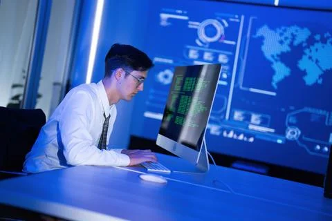 Young man coding in a modern office with blue lighting and data visualizati.. Stock Photos