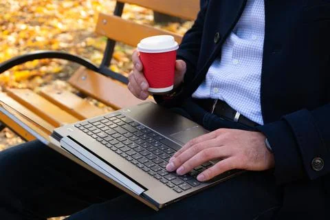 Young man with coffe and using laptop in the autumn park. Stock-Fotos