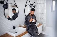 Young Man With Coffee And Bathrobe Indoors In Bathroom At Home, Taking Selfie. Stock Photos