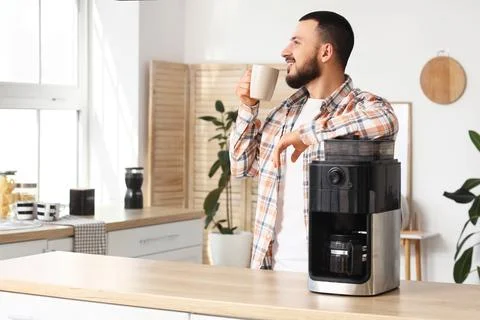Young man with coffee machine drinking espresso in kitchen Stock Photos