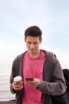 Young man with a coffee using a mobile phone Stock Photos