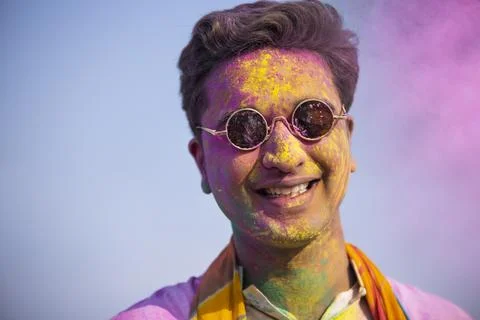 A young man with colour on his face is happily posing in front of camera Stock Photos