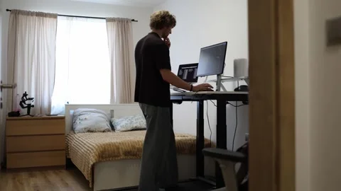 Young man combines computer work with exercise while walking on a treadmill Stock Footage 346881808