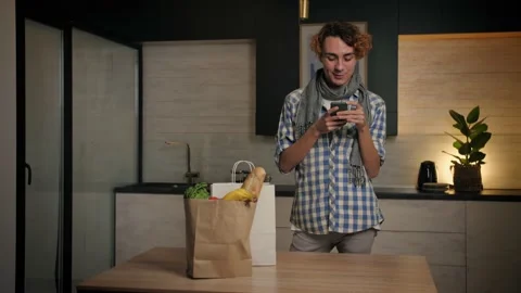 Young Man come home from store carrying paper bag with food in kitchen.Checking Stock Footage 221618713