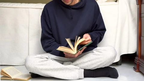 Young man in comfortable clothes turning the pages of an old book next to a w Stock Footage 167089515
