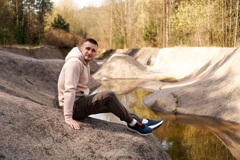 Young man in a comfortable suit at the edge of a rowing canal or mountain river Stock Photos
