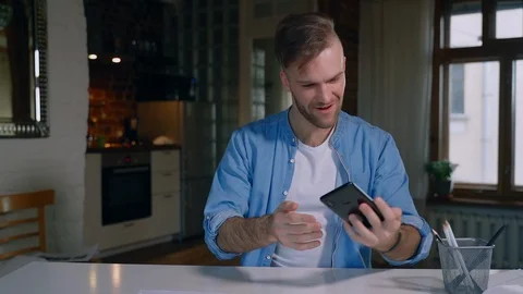Young man communicates in video chat using smartphone during self-isolation in Stock Footage 128970797
