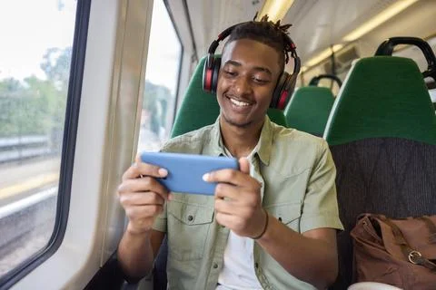Young Man Commuting To Work Sitting  On Train Streaming And Watching Film O.. Stock Photos