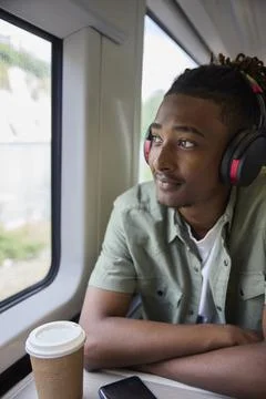 Young Man Commuting To Work Sitting  On Train Wearing Wireless Headphones L.. Stock Photos