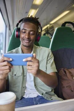 Young Man Commuting To Work Sitting  On Train Streaming And Watching Film O.. Stock Photos