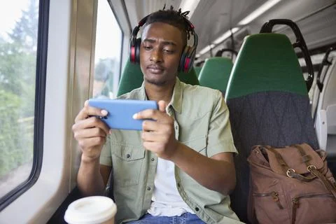 Young Man Commuting To Work Sitting  On Train Streaming And Watching Film O.. Stock Photos