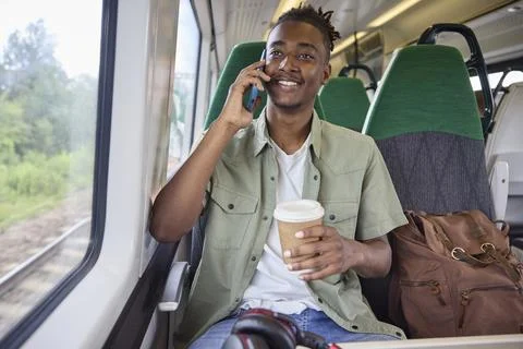 Young Man Commuting To Work On Train Sitting  On Train Talking On Mobile Ph.. Foto stock