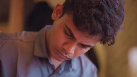Young man with concentrated expression leans forward with downward gaze Stock Footage 318252802