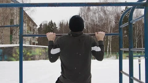 Young man conducts workout pulls up on a metal horizontal bar on the outdoors Stock Footage 150062898