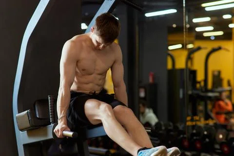 A young man confidently doing dips in a modern gym, showing dedication to his Foto stock