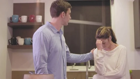 Young man consoling his distressed girlfriend in a kitchen Stock Footage 83020544