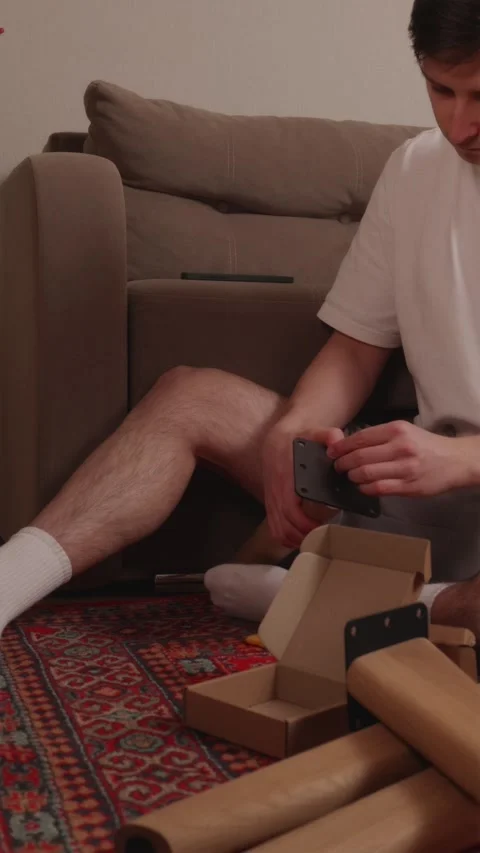 Young man constructing wooden table on living room floor Stock-Footage 346396660