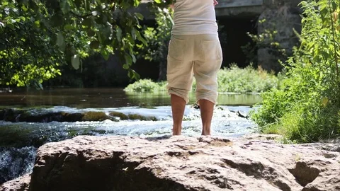 Young man contemplates the flowing river on a summer day Video stock 84025825