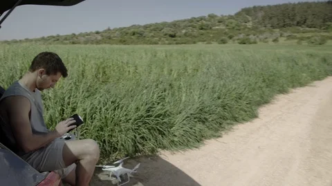 Young man controlling drone standing in the field with a remote his In hands. Stock Footage 116152607